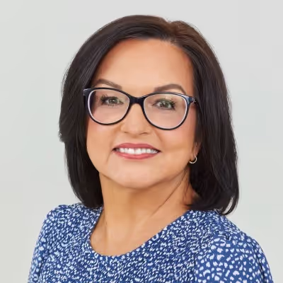 Smiling professional woman with glasses wearing blue patterned blouse